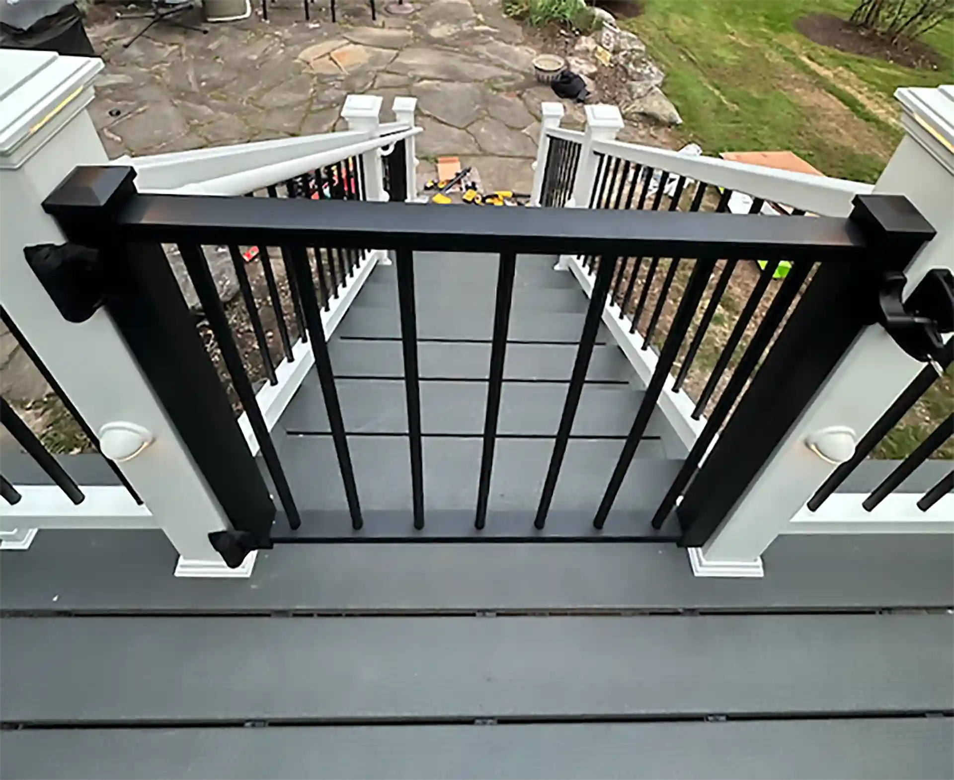 View of a Trex composite deck with black metal railing and white posts.