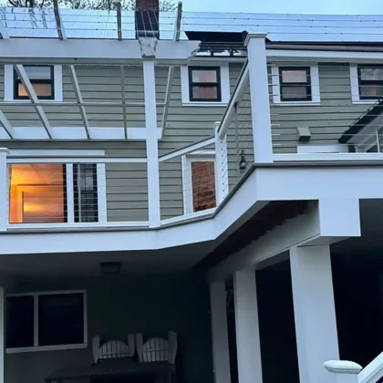 A multi-level deck with cable railings, a shaded upper level, and a covered lower area beneath, providing additional functional space.