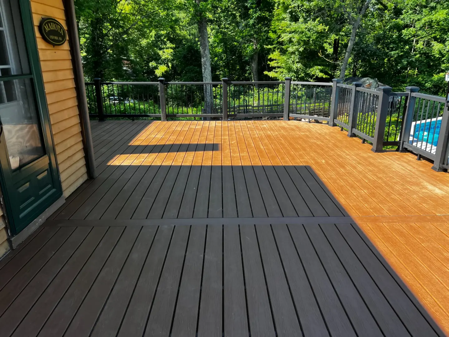 hard-wood-deck-with-black-railing-featuring-trees-in-the-background-in-bolton-ma