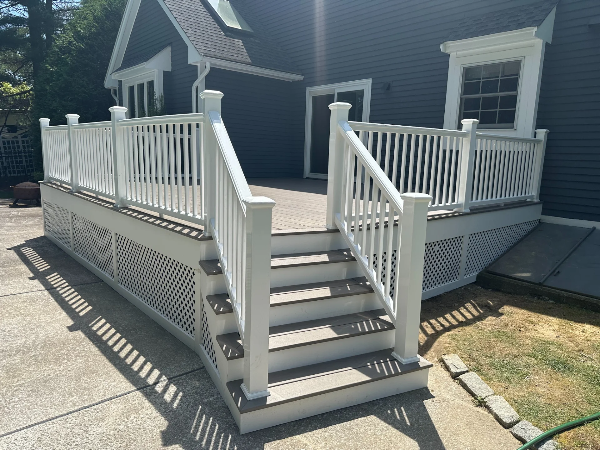 white-railing-on-a-deck-with-skirting-in-front-of-blue-house-in-bolton-ma